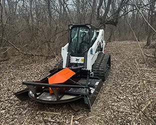 Bobcat loader with Brushcat rotary cutter attachment on land clearing project